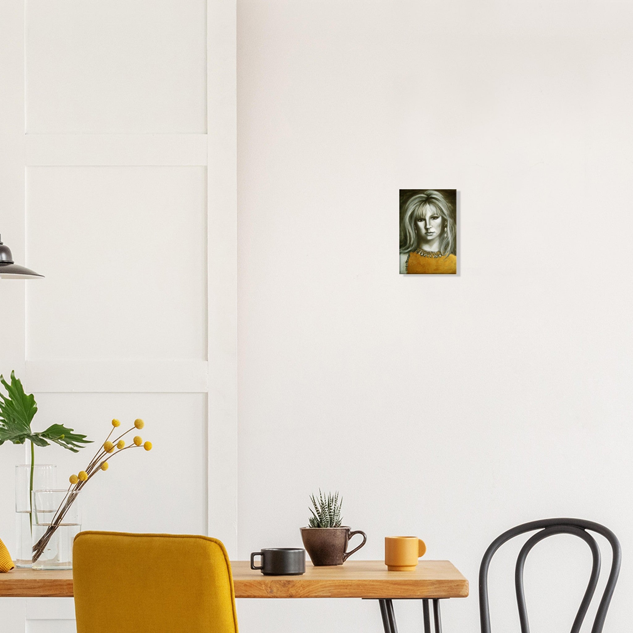 Modern dining area with yellow chair, wooden table, plant, and small portrait painting on white wall