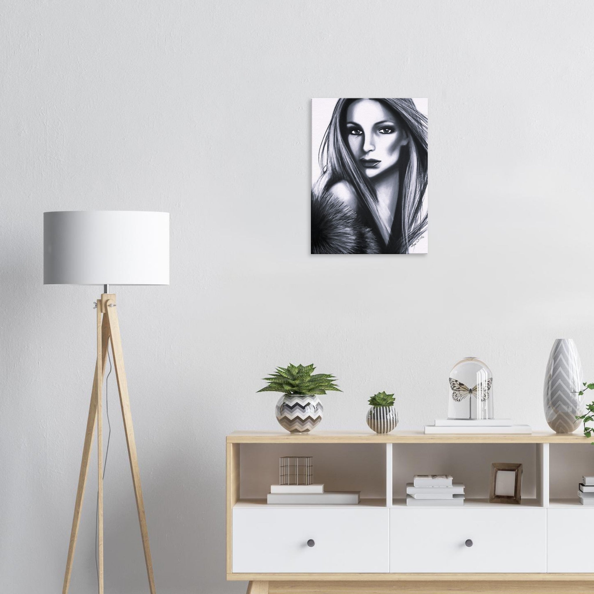 Modern interior with black and white female portrait art, wooden floor lamp, and decorative plants on sideboard